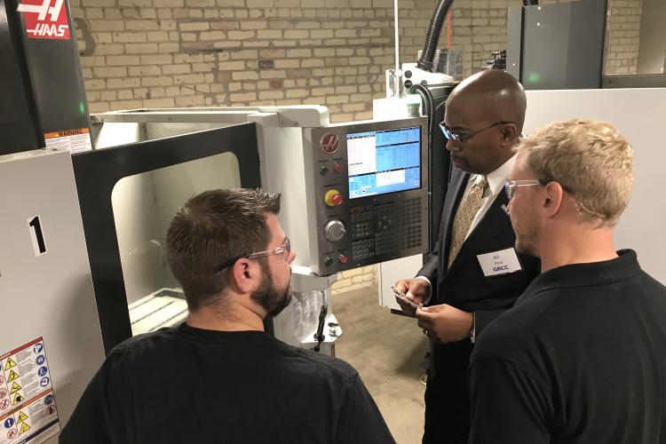 GRCC President Bill Pink with two students looking at machinery at the AMP Lab