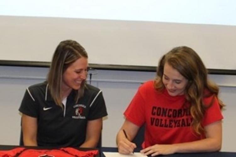 Lena Thompson signs a document as a Concordia University staffer watches.