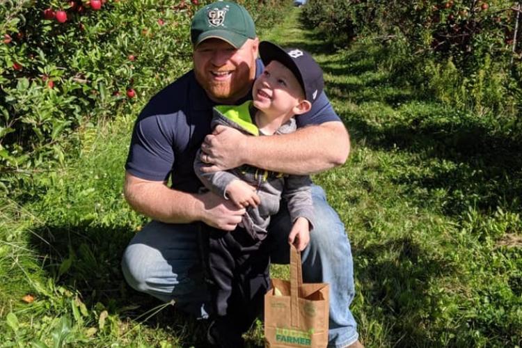 Saniel Schoonmaker with a child in an orchard.