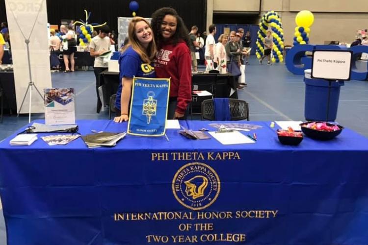 Phi Theta Kappa students behind their table promoting their program at a campus event.