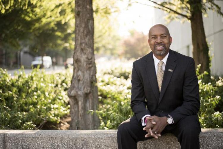 President Bill Pink sits on a low concrete wall.