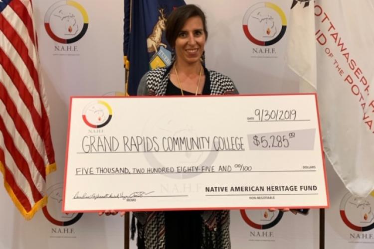 Rachel Beecher holds up a giant check for $5,285 from the Native American Heritage Fund.