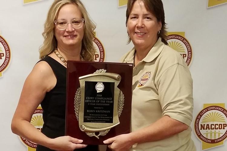 Officer Robin Kritzman receives a plaque from a member of the National Association of Clery Compliance Officers and Professionals.