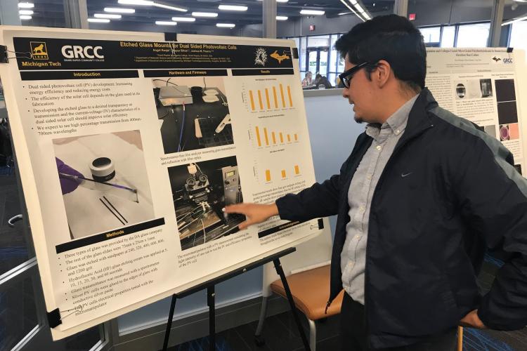 A TRIO student pointing to a display of his summer research from 2019.