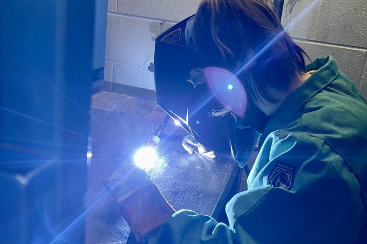 Marissa in the shop welding.