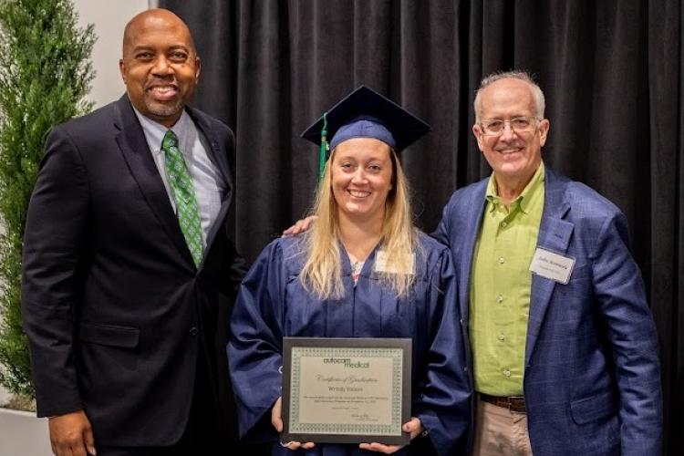 Wrindy Hauser posing with GRCC President Pink and Autocam's John Kennedy at commencement.