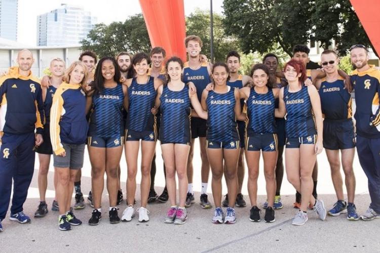 The coaches and members of the men's and women's cross country teams stand under the Calder.