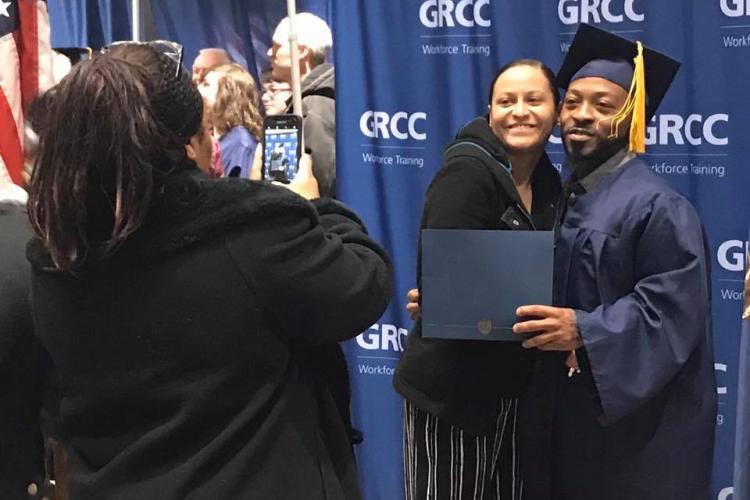 A woman takes a photo of a Job Training graduate and a young woman.