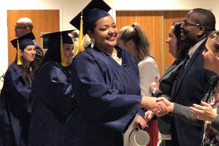 A Medical Assistant graduate shakes Amy Mansfield's hand.