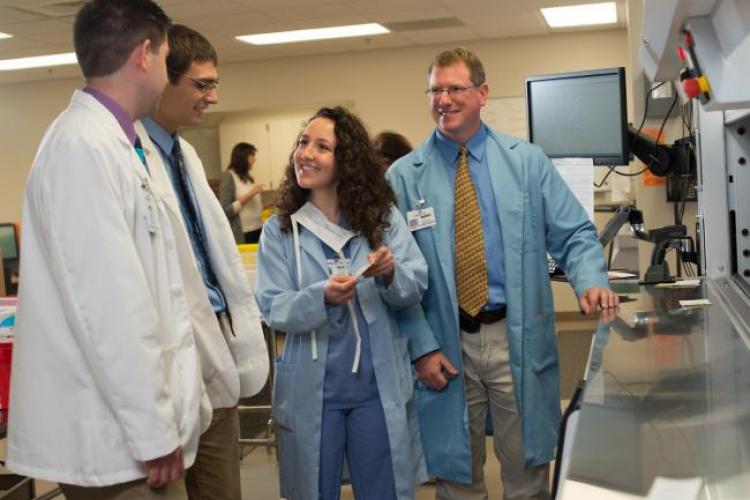 Students and doctors in lab coats working together.