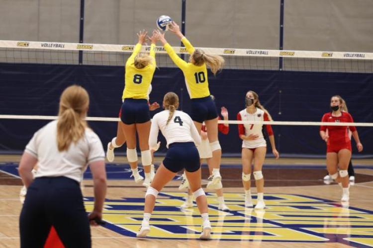 GRCC volleyball players jumping for a block.