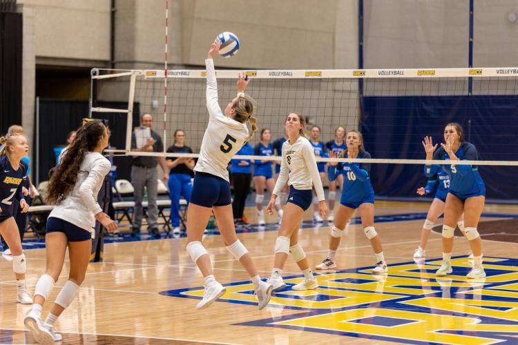 GRCC volleyball players leaping for the ball.