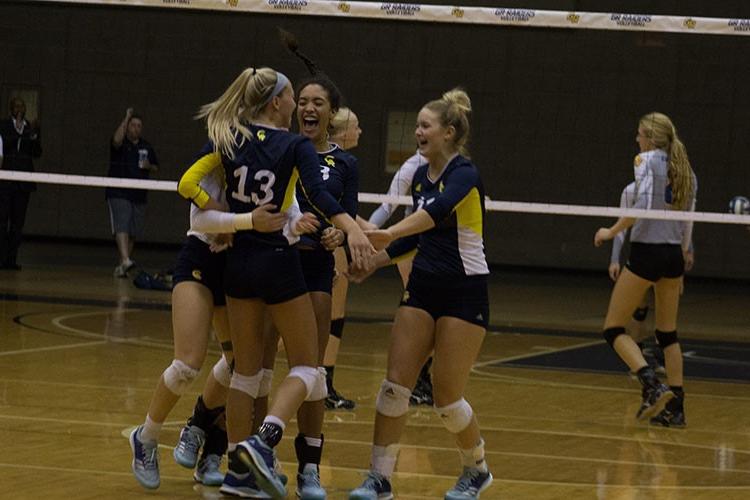 Members of the volleyball team hug in front of the net.