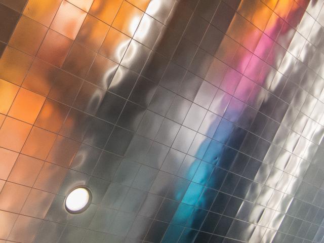 A metal-clad ceiling reflecting a rainbow of colors from the carpet below.