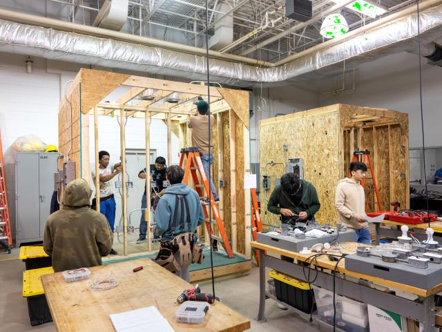 Students work on wiring in a demonstration construction unit. 